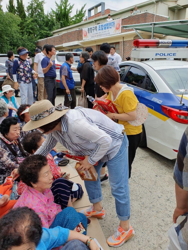 사진 = 시공사 홍보요원들이 집회에 참석한 조합원들에게 빵을 나눠주고 있는 모습.