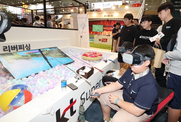 KVRF 방문 고객들이 KT 전시관에서 슈퍼VR 낚시 게임을 체험하고 있다.