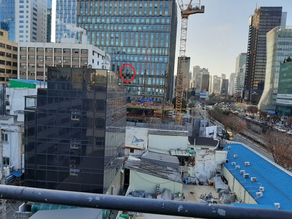 CJ건설이 시공 중인 한 건물 건설현장에서 한 근로자가 7~8m 이상의 높이의 철골구조물 위에서 위태롭게 작업 중이다.