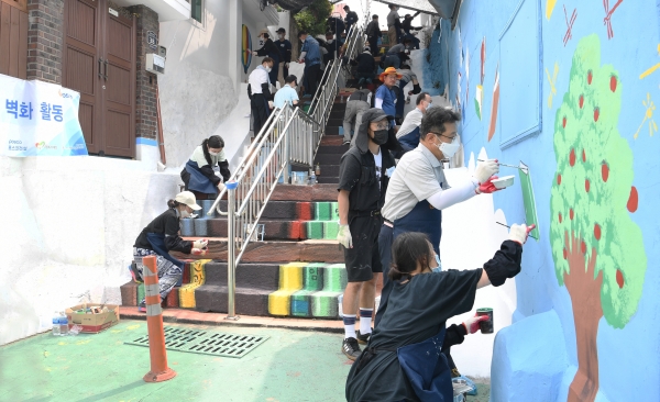 사진 = 포스코건설 봉사단원들이 배다리마을 계단에서 벽화그리기 봉사활동을 실시하고 있다. (포스코건설 제공)