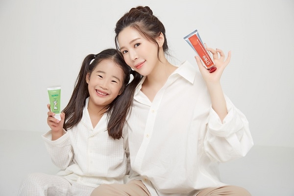 배우 겸 가수인 김추리가 어린이 모델과 함께 스티치약을 들고 환하게 웃고 있다.