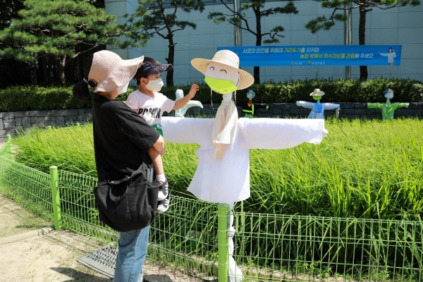 한 시민이 아이와 함께 서울시 중구 농업박물관 야외체험장에 설치된 허수아비를 관람하고 있다.[사진 농협 제공]