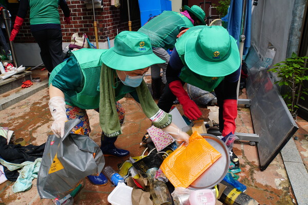 자원봉사자들이 토사가 묻은 침수가구 집기류를 밖으로 꺼내고 있다 (사진=서울시 보도자료)